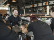 Nick Yahn of Battle Ground, a WildFin American Grill bartender, laughs while practicing menu cocktails with the rest of the bartending staff during training at The Vancouver Waterfront on Thursday morning.