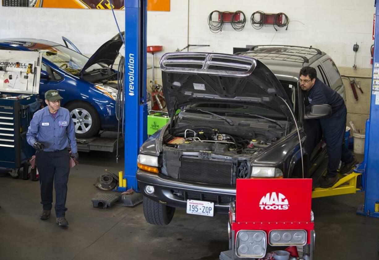 Left: Butch Brawner of Hoesly Eco Automotive, left, and colleague Fernando Sanchez work on cars for customers Tuesday morning.