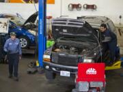 Left: Butch Brawner of Hoesly Eco Automotive, left, and colleague Fernando Sanchez work on cars for customers Tuesday morning.