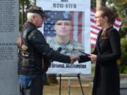 Lynn Vaughn, left, district captain of the Southwest Washington chapter of the Patriot Guard Riders, hands Nina Wilson, widow of Army Chief Warrant Officer 2 Jonah McClellan, a plaque honoring McClellan, who died eight years ago Friday in Afghanistan.