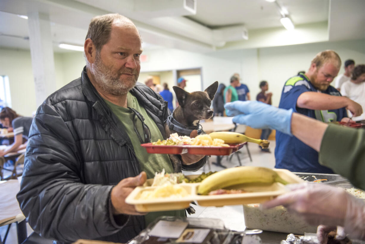 Ray Vanderslice and his Chihuahua mix, Rocky, 5, collect lunch in the newly remodeled Share House cafeteria on Wednesday. “It’s cuter,” Vanderslice said of the updated space. The men’s homeless shelter spent the summer remodeling its kitchen and ground-floor restrooms, as well as floors and lighting.