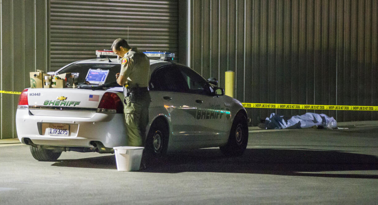 A Kern County sheriff's deputy stands near an area where a shooting victim lies, Wednesday, Sept. 12, 2018, in Bakersfield, Calif. A gunman killed five people, including his wife, before turning the gun on himself, authorities said.