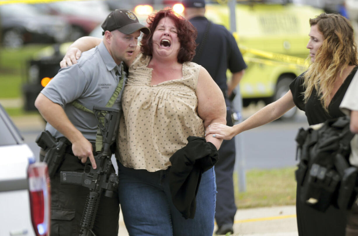 A women is escorted from the scene of a shooting at a software company in Middleton, Wis., on Wednesday. Four people were shot and wounded during the shooting in the suburb of Madison, according to a city administrator.