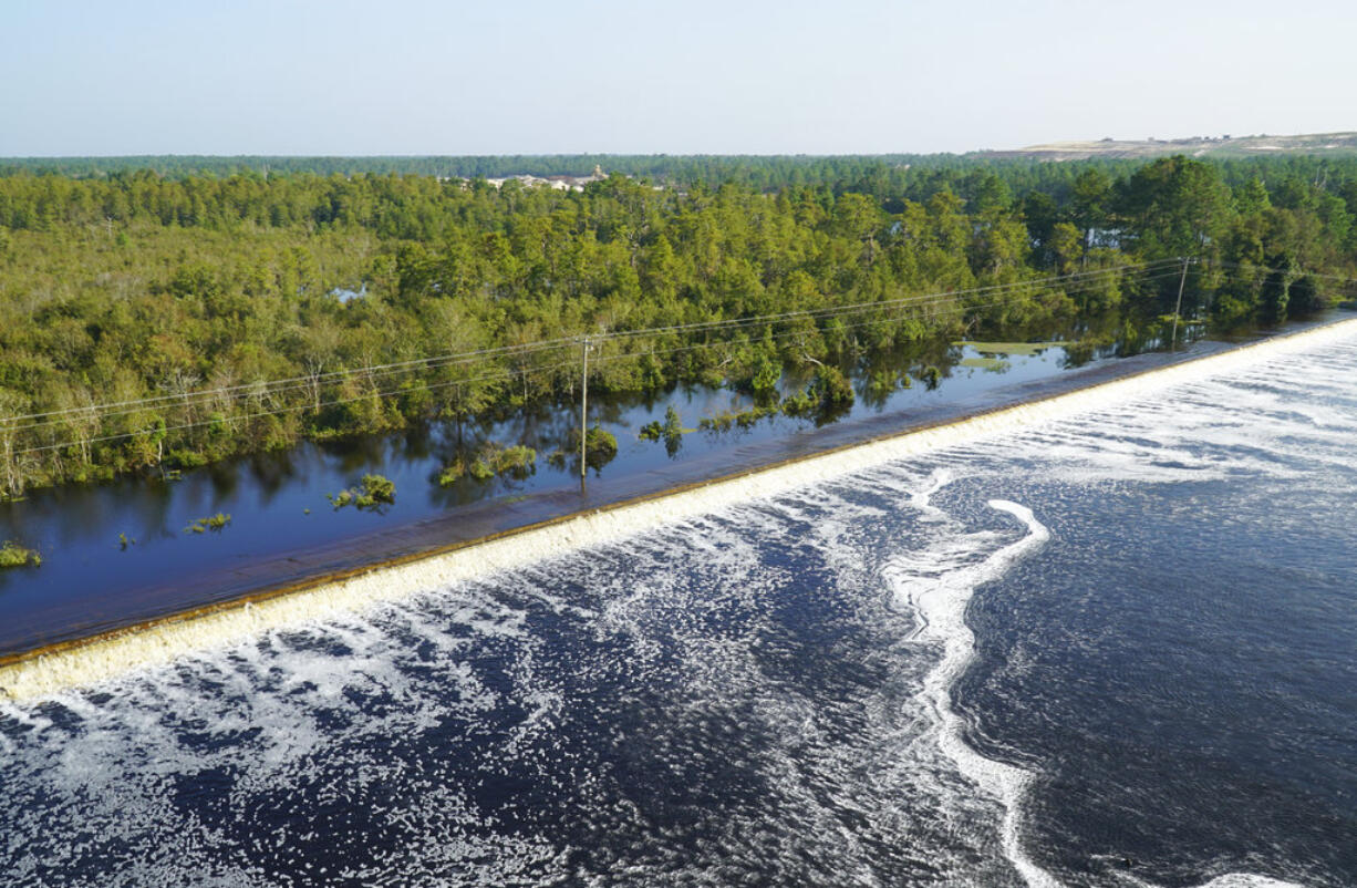 In this drone photo released by Duke Energy, flooding from the swollen Cape Fear River overtops an earthen dike at Sutton Lake, a 1,100-acre (445-hectare) lake at the L.V. Sutton Power Station near Wilmington, N.C. , Thursday, Sept. 20, 2018. Duke Energy activated a high-level emergency alert at the retired coal-fired power plant due to the flooding, raising concerns of a potential breach.