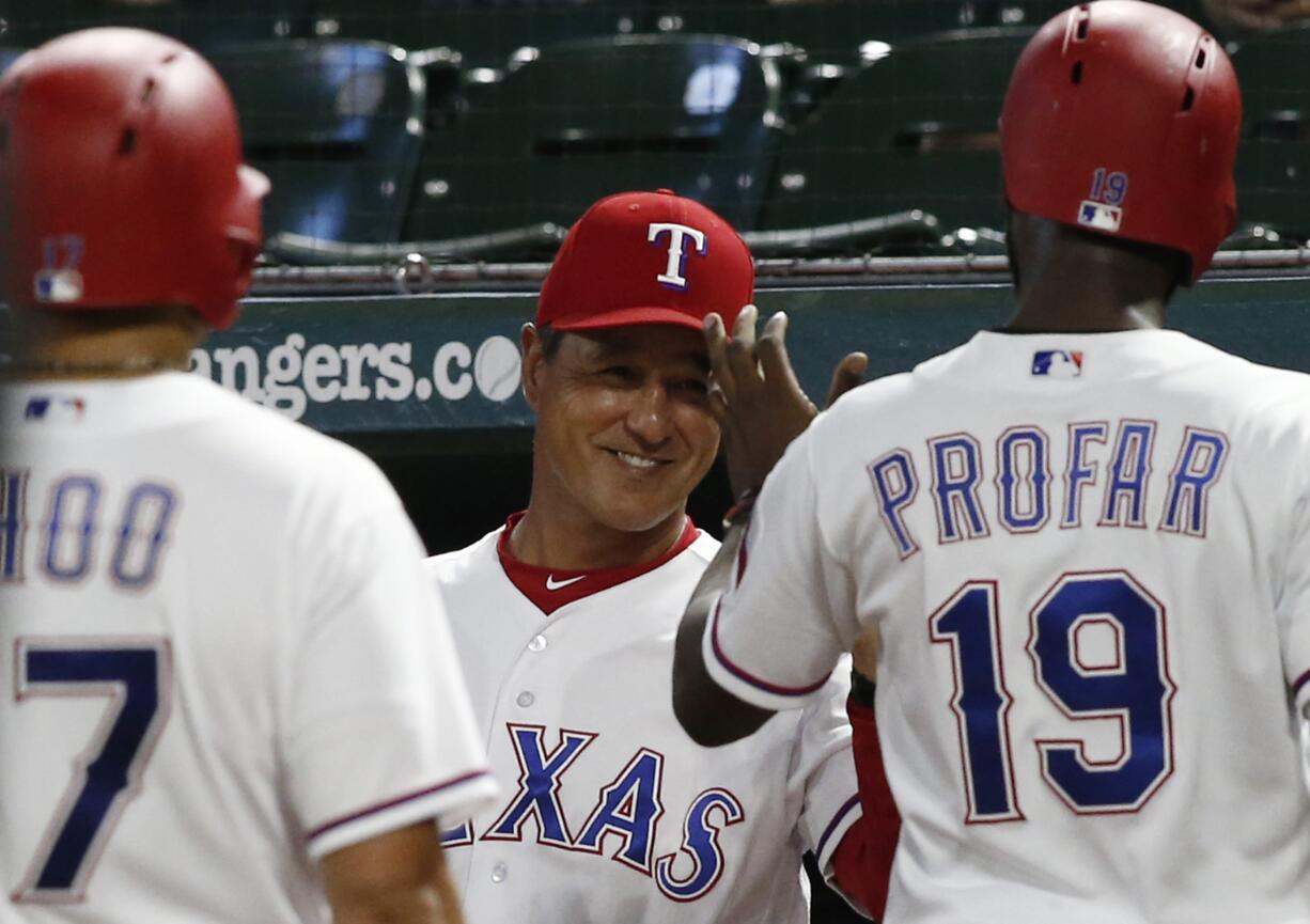 Texas Ranger interim manager Don Wakamatsu, center, congratulates Shin-Soo Choo and Jurickson Profar (19) after they scored on a single by Adrian Beltre against the Seattle Mariners during the third inning of a baseball game Friday, Sept. 21, 2018, in Arlington, Texas.