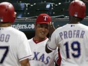 Texas Ranger interim manager Don Wakamatsu, center, congratulates Shin-Soo Choo and Jurickson Profar (19) after they scored on a single by Adrian Beltre against the Seattle Mariners during the third inning of a baseball game Friday, Sept. 21, 2018, in Arlington, Texas.