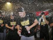 Oakland Athletics' Trevor Cahill is doused in the clubhouse celebration after clinching a wild card spot after the baseball game against the Seattle Mariners, Monday, Sept. 24, 2018, in Seattle.