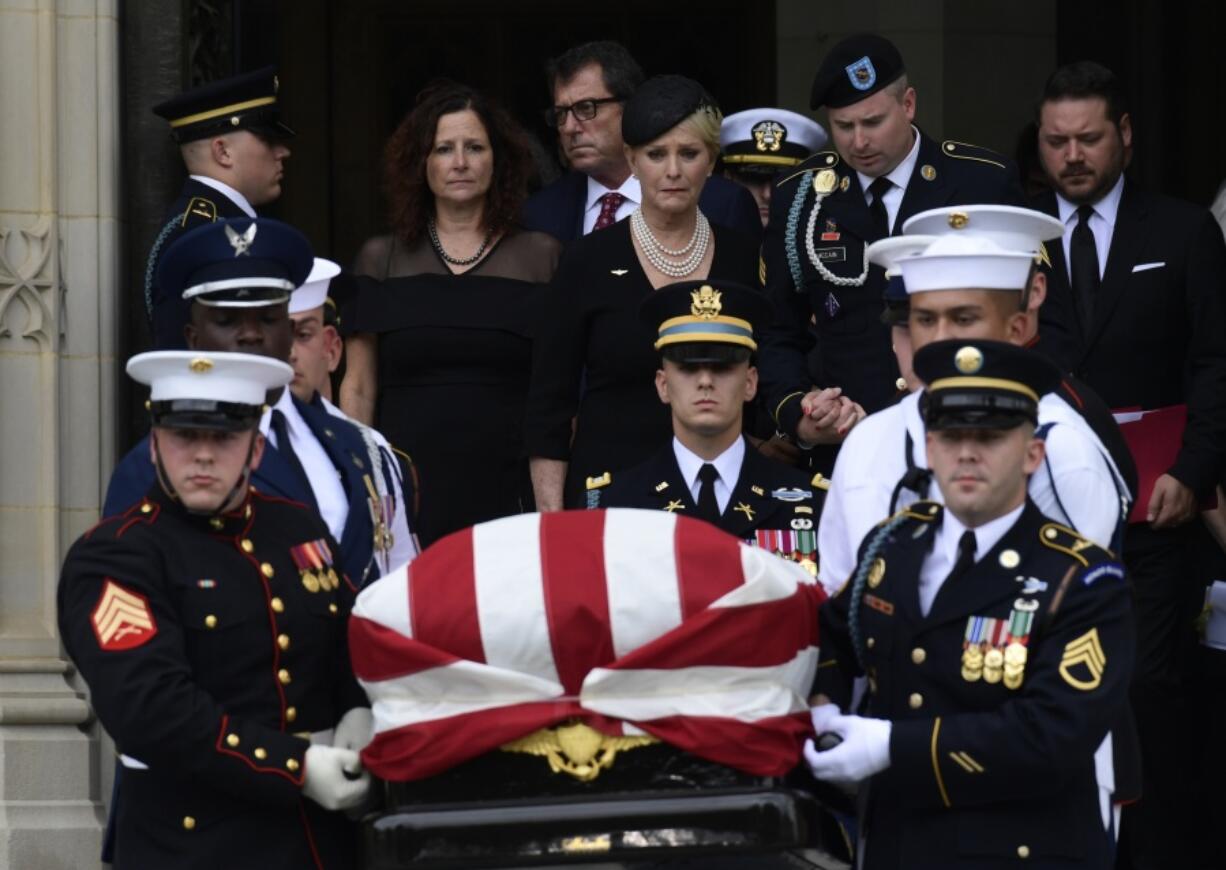 The casket of Sen. John McCain, R-Ariz., is carried out of the Washington National Cathedral in Washington, Saturday, Sept. 1, 2018, after a memorial service, as Cindy McCain is escorted by her son Jimmy McCain and other family members.