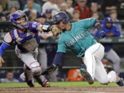 Seattle Mariners’ Jean Segura, right, avoids a tag by Texas Rangers catcher Robinson Chirinos while sliding safely home in the second inning of a baseball game Friday, Sept. 28, 2018, in Seattle.