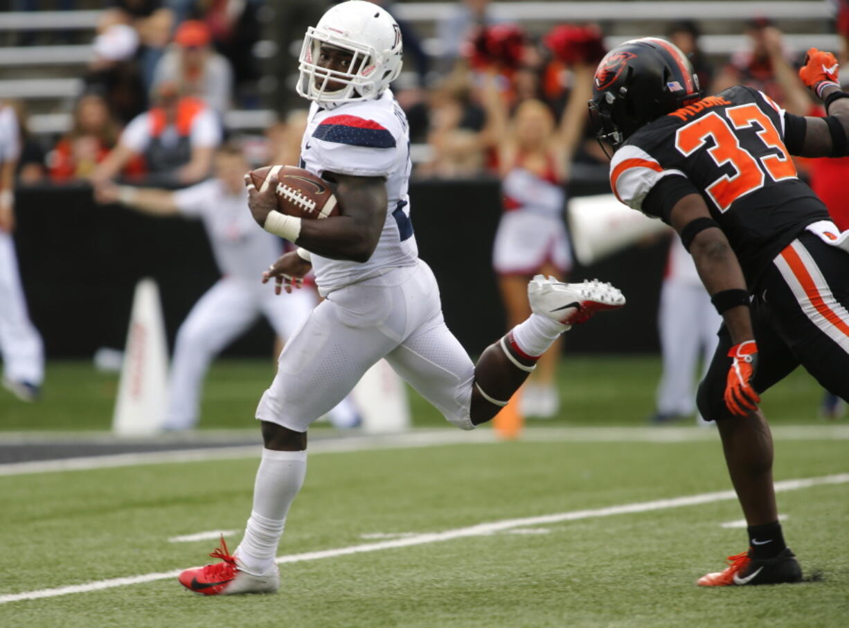 Arizona running back J.J. Taylor looks back at Oregon State’s Jalen Moore as he heads to the end zone on a 62 run in the fourth quarter of an NCAA college football game in Corvallis, Ore., Saturday, Sept 22, 2018. Arizona won 35-14. (AP Photo/Timothy J.