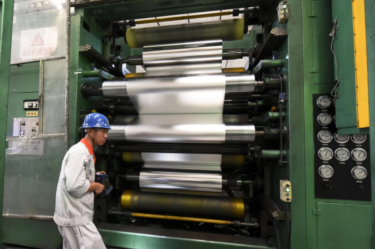 In this Thursday, Sept. 13, 2018, photo, a worker handles a machine roller at an aluminium factory in Zouping in eastern China’s Shandong province. China announced more tariff cuts Wednesday, Sept. 26, on construction machinery and other goods but no action on U.S. complaints about its technology policy that are fuelling an escalating trade battle.