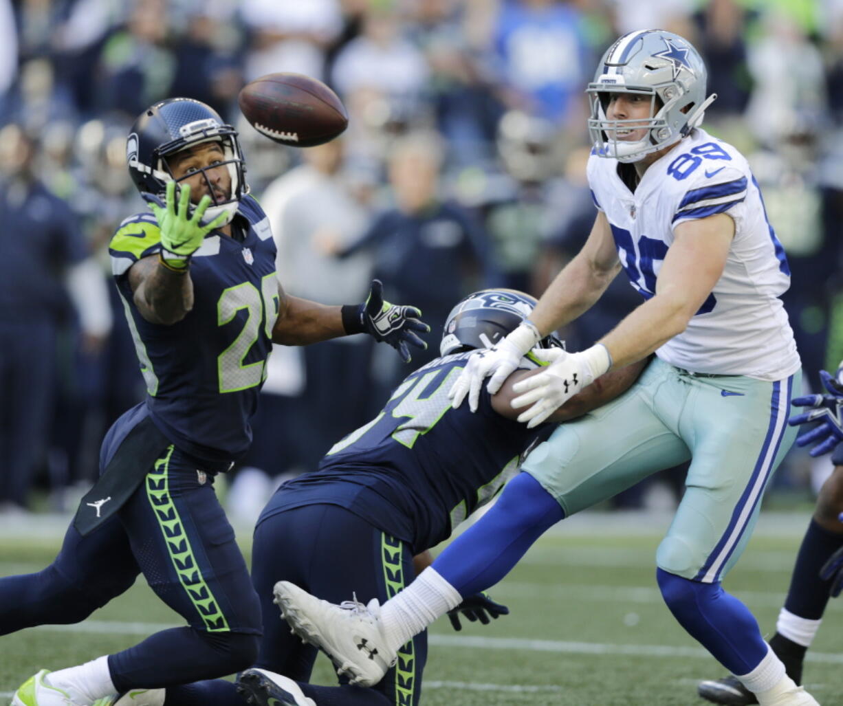 Seattle Seahawks free safety Earl Thomas, left, reaches for a pass he intercepted that was intended for Dallas Cowboys tight end Blake Jarwin, right, as Seahawks’ Bobby Wagner, center, looks on during the second half of an NFL football game, Sunday, Sept. 23, 2018, in Seattle. The pick was Thomas’ second of the game.