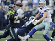 Seattle Seahawks free safety Earl Thomas, left, reaches for a pass he intercepted that was intended for Dallas Cowboys tight end Blake Jarwin, right, as Seahawks’ Bobby Wagner, center, looks on during the second half of an NFL football game, Sunday, Sept. 23, 2018, in Seattle. The pick was Thomas’ second of the game.