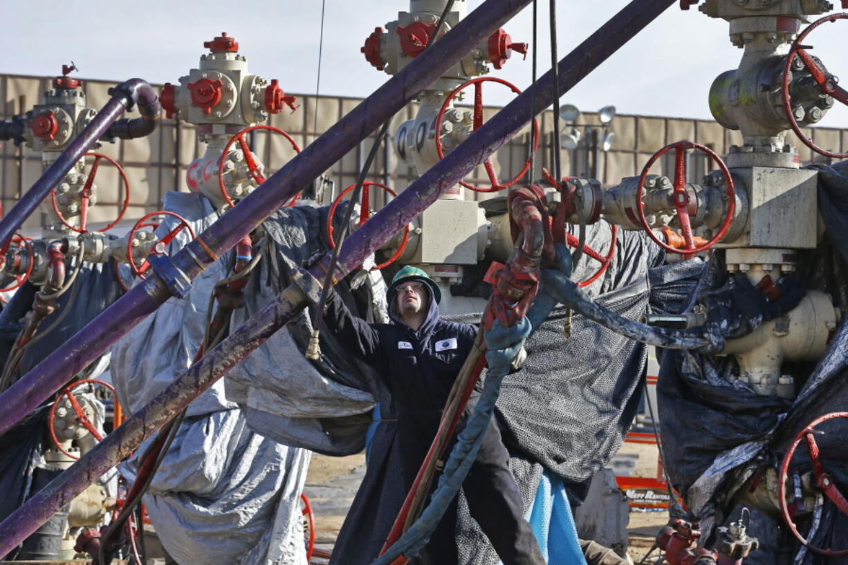 A worker adjusts pipes March 25, 2014, during a hydraulic fracturing operation at a well pad near Mead, Colo. The Trump administration is moving to roll back Obama-era rules intended to reduce leaks of climate-changing methane from oil and gas facilities.