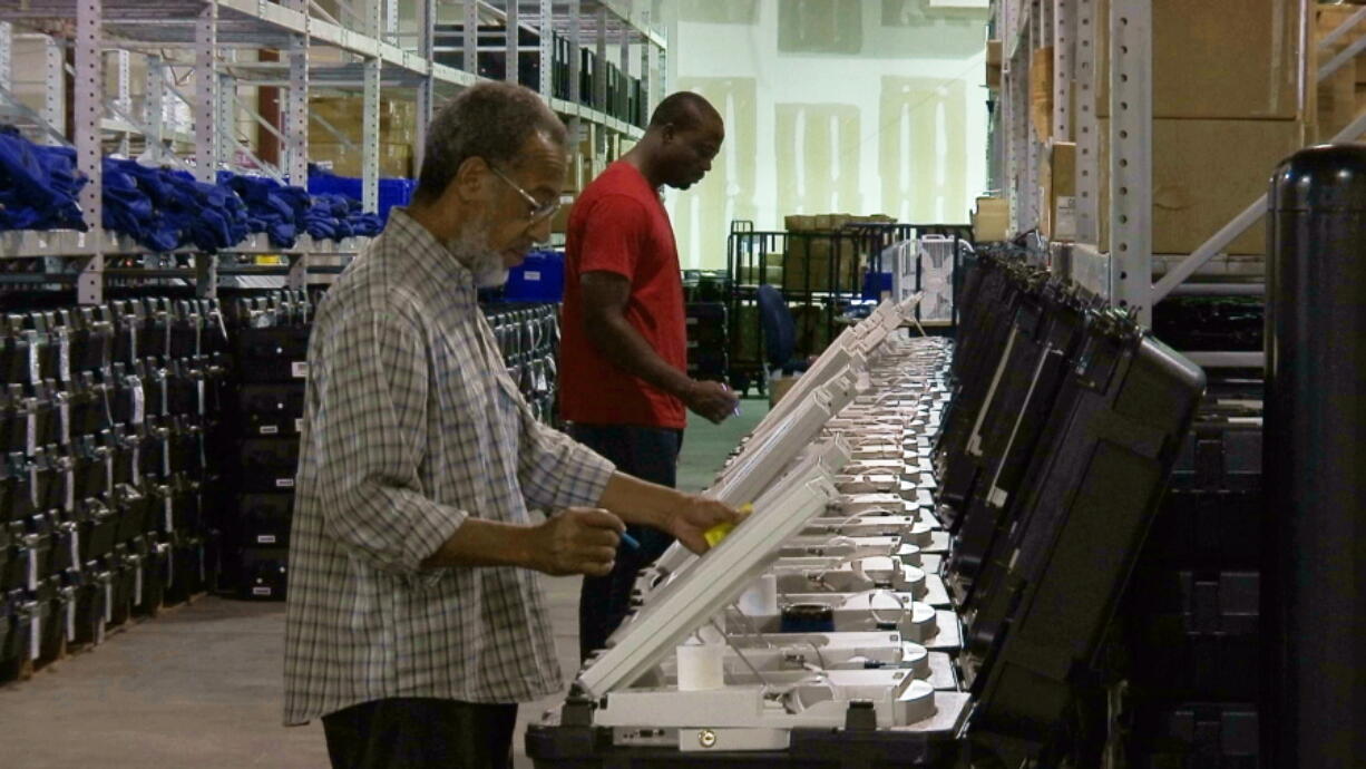 Employees of the Fulton County Election Preparation Center in Atlanta test electronic voting machines. Voting integrity advocates had argued Georgia’s electronic voting machines are unreliable and vulnerable to hacking, but a federal judge says forcing the state to change its system to paper ballots before the midterm elections is too risky.