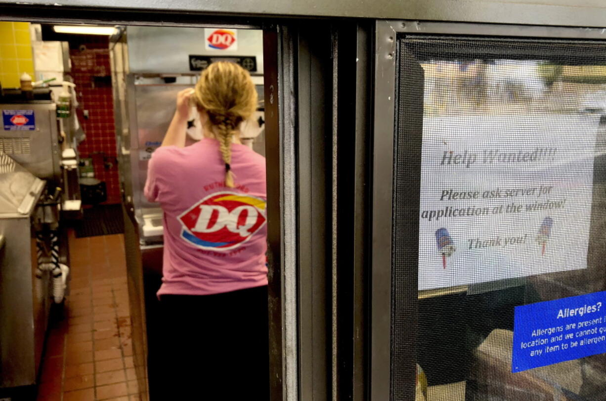 Awoman prepares a cup of ice cream behind a “Help Wanted” sign at a Dairy Queen fast food restaurant in Rutherford, N.J. On Tuesday, Sept. 11, the Labor Department reports on job openings and labor turnover for July.