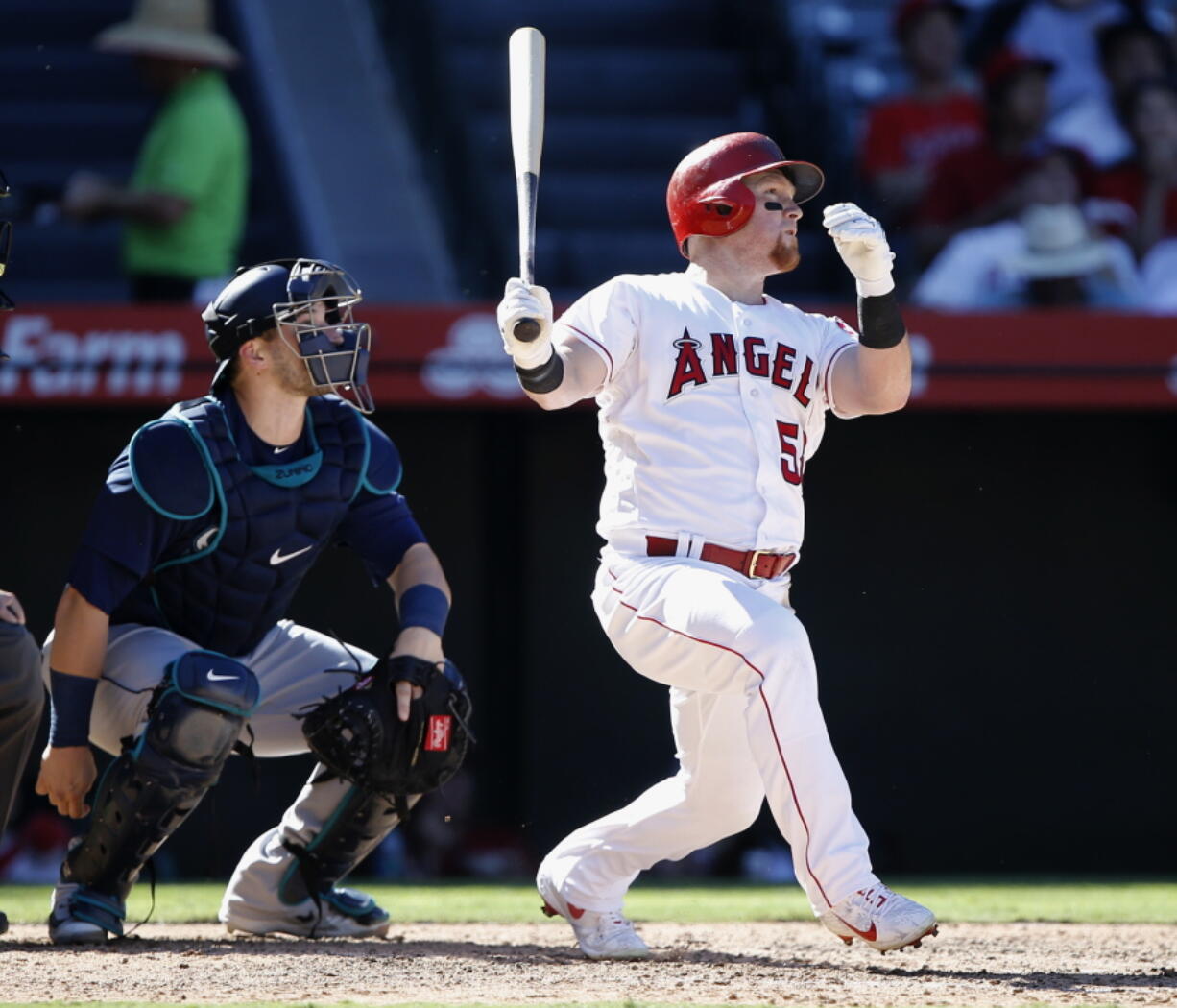 Los Angeles Angels’ Kole Calhoun, right, hits a solo home run with Seattle Mariners catcher Mike Zunino watching during the seventh inning of a baseball game in Anaheim, Calif., Sunday, Sept. 16, 2018.