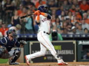 Houston Astros’ Marwin Gonzalez, right, hits a two-run home run as Seattle Mariners catcher Chris Herrmann watches during the third inning of a baseball game Tuesday, Sept. 18, 2018, in Houston. (AP Photo/David J.