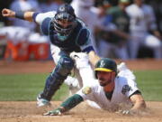 Oakland Athletics’ Matt Joyce slides to score beneath the tag of Seattle Mariners catcher Mike Zunino in the sixth inning of a baseball game Sunday, Sept. 2, 2018, in Oakland, Calif. Joyce scored on a single by A’s Marcus Semien.