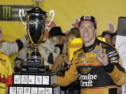 Brad Keselowski stands by his trophy after winning the NASCAR Cup Series auto race at Darlington Raceway, Sunday, Sept. 2, 2018, in Darlington, S.C.