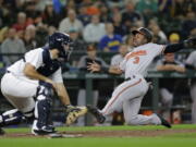 Baltimore Orioles’ Cedric Mullins scores on a ball hit by Jonathan Villar with Seattle Mariners catcher David Freitas waiting for the throw during the seventh inning of a baseball game Tuesday, Sept. 4, 2018, in Seattle.