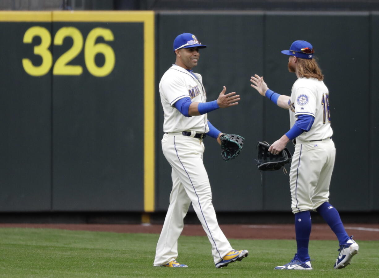 Seattle Mariners' Nelson Cruz, left, is greeted by Ben Gamel, right, as Gamel arrives to replace Cruz in right field during the fourth inning of a baseball game against the Texas Rangers, Sunday, Sept. 30, 2018, in Seattle. (AP Photo/Ted S.