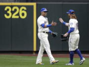 Seattle Mariners' Nelson Cruz, left, is greeted by Ben Gamel, right, as Gamel arrives to replace Cruz in right field during the fourth inning of a baseball game against the Texas Rangers, Sunday, Sept. 30, 2018, in Seattle. (AP Photo/Ted S.