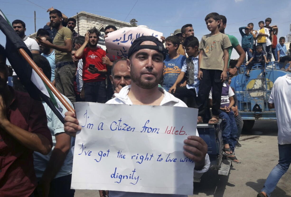 This image courtesy of Mustafa Alabdullah, an activist and resident of Idlib, shows a protester holding a placard, in Harim, a town in Idlib province, Syria, Friday, Sept 7, 2018. The rallies were part of a day of protests against Syrian President Bashar Assad and his troops’ imminent offensive against Idlib, the last bastion of rebels in Syria. The Friday rallies came as Presidents of Iran, Turkey and Russia are meeting in Tehran to discuss the war in Syria. The summit may determine whether diplomacy halts any military action in Idlib and its surrounding areas, home to more than 3 million people. Nearly half of the area’s residents are already displaced from other parts of Syria and have refused to reconcile with the Syrian government.