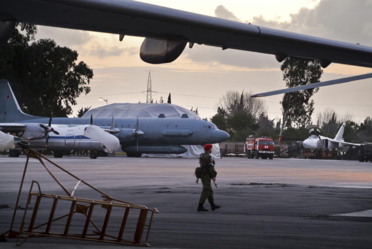 A Russian military police officer stands guard at the Russian air base in Hemeimeem, Syria, with an Il-20 electronic intelligence plane of the Russian air force in the background. Russia is determined to keep Syria solidly anchored in its sphere of influence over the long term - both as a foothold in the Middle East and as a warning to the U.S. and its allies against future interference. Russian forces proved decisive in the international struggle against the Islamic State group, giving Moscow a credibility that Western powers lack.