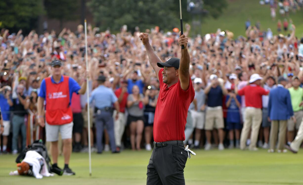 Tiger Woods celebrates after picking up his putt for par on the 18th green to win the final round of the Tour Championship golf tournament Sunday, Sept. 23, 2018, in Atlanta.