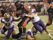 Utah running back Zack Moss (2) is tackled by Washington’s Ben Burr-Kirven (25), Greg Gaines (99) and Tevis Bartlett (17) Saturday in Salt Lake City.