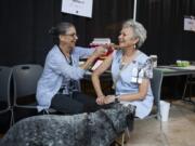 Registered nurse Eileen Langford, left, administers a flu shot to hospital volunteer Gail Greer during the Kick The Flu event for hospital employees at Legacy Salmon Creek Medical Center. Greer and her dog, Truman, are volunteers with the hospital’s Pet Partners animal therapy program.