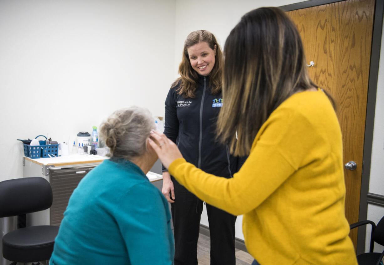 Pain Relief Partners owner and nurse practitioner Stephanie Jones, center, checks in with Anna Sasin, left, and Sasin’s daughter Anna Gridin, right, both of Portland, after Jones treated Sasin at Pain Relief Partners.