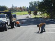 Miguel Martinez of Patriot Sealcoat, Inc., right, helps with the installation of pavement markings in a subdivision under construction south of The Cedars on Salmon Creek on Thursday afternoon.