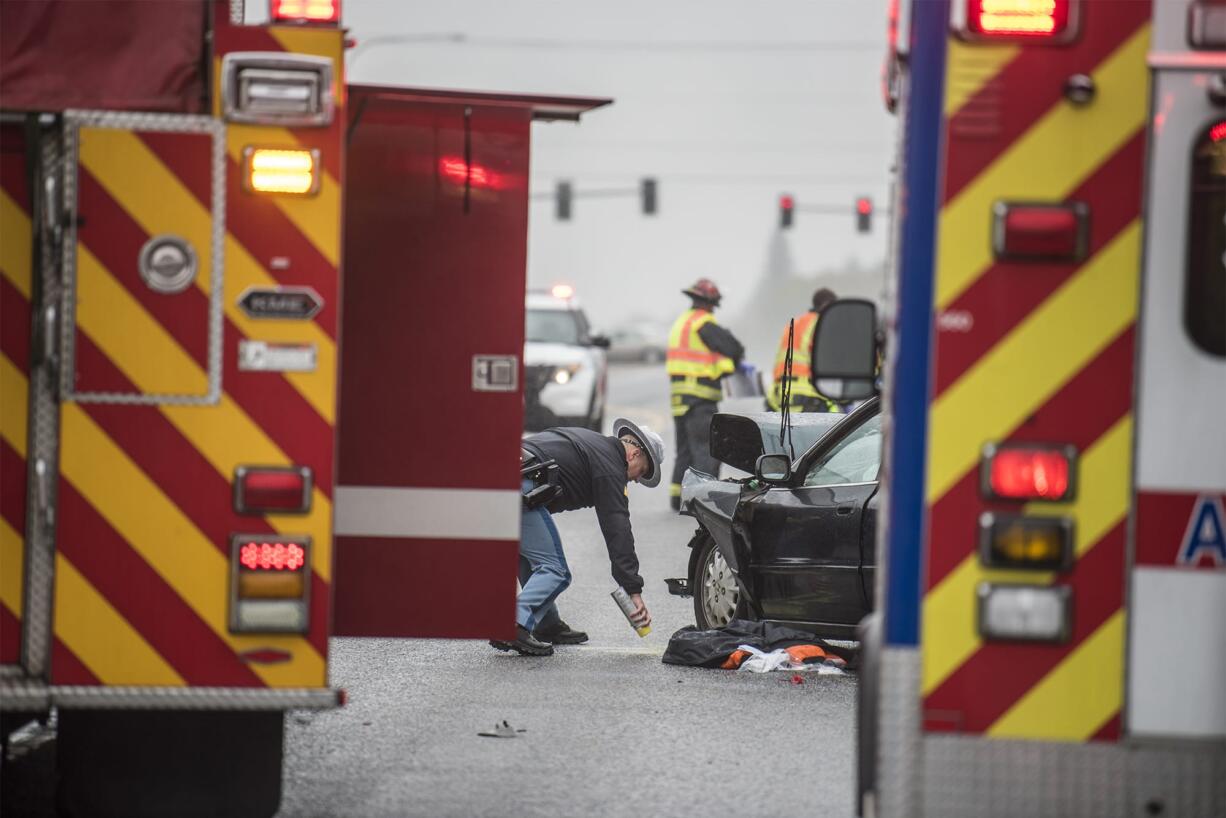 A state patrol trooper marks the ground at the scene of an accident on state Highway 500 on Monday afternoon.