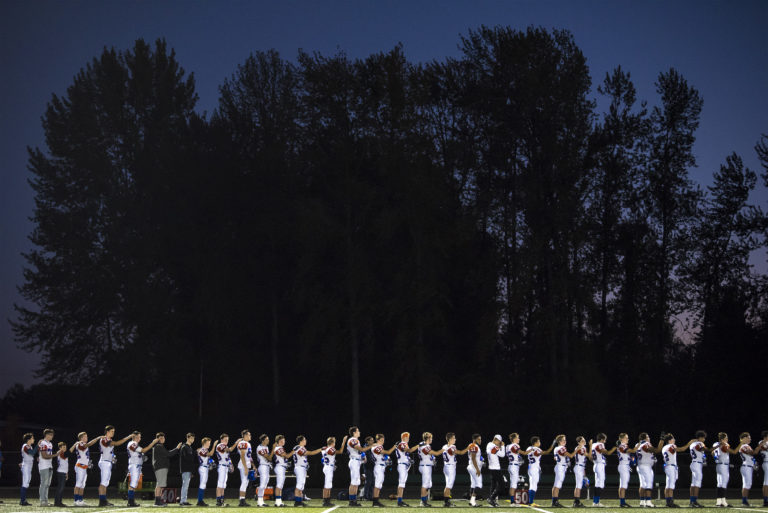 Ridgefield listens to the national anthem at the start of their match against Woodland at Woodland High School on Friday night, Oct. 12, 2018.