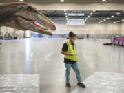 Ricky Rodriguez with Jurassic Quest stops to think in front of a dinosaur while working on a display at the Clark County Event Center at the Fairgrounds on Thursday afternoon. The exhibit opened Friday and features more than 100 animatronic dinosaurs.