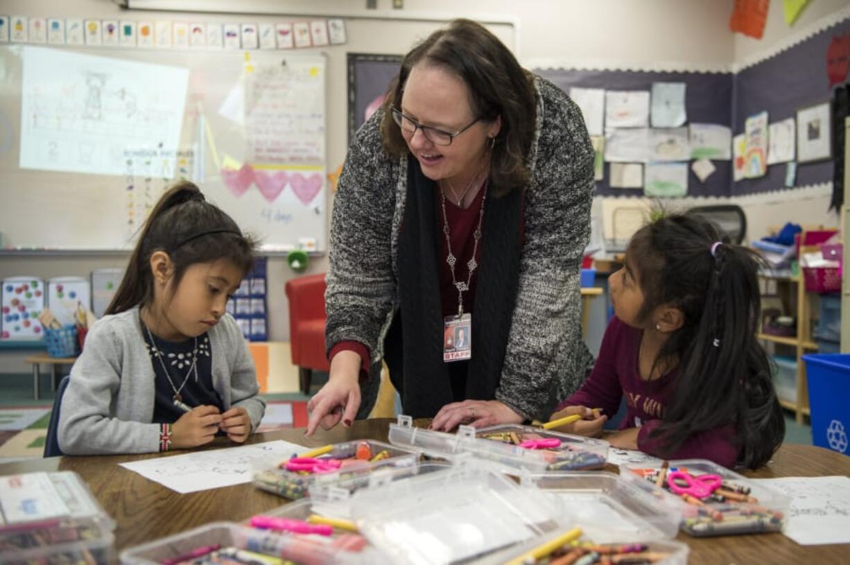 Principal Ingrid Colvard helps Camila Garcia Vasquez, left, and Elisa Martinez Lopez with an alphabet exercise in one of the dual language kindergarten classes at Woodland Primary School.