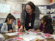 Principal Ingrid Colvard helps Camila Garcia Vasquez, left, and Elisa Martinez Lopez with an alphabet exercise in one of the dual language kindergarten classes at Woodland Primary School.