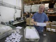 Nathan Stewart, foreground, and Mark Furlong sort election ballots Wednesday as they prepare them to mail to Clark County voters. The county contracts with Send It Direct Mail, a company based in Portland, to get the ballots out.