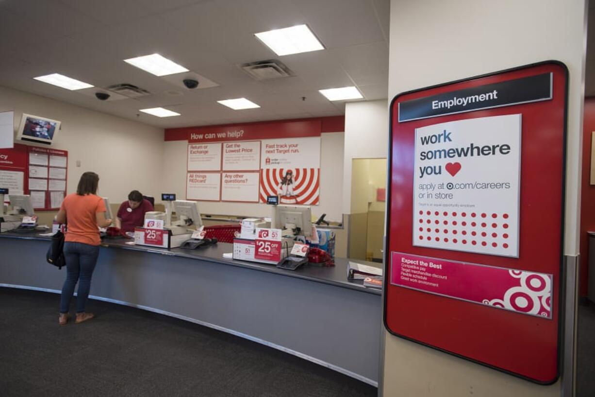 A sign advertises careers available at the Hazel Dell Target as engagement advocate Daphne Jones, in maroon, assists customer Erika Carlsen of Vancouver on Wednesday.