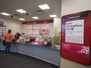 A sign advertises careers available at the Hazel Dell Target as engagement advocate Daphne Jones, in maroon, assists customer Erika Carlsen of Vancouver on Wednesday.