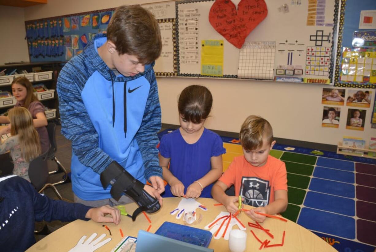 Washougal: Jemtegaard Middle School’s Jaden Cooms, from left, helps Columbia River Gorge Elementary School first-graders Ella Paulson and Tucker Morgan on a project to learn how the human hand works.