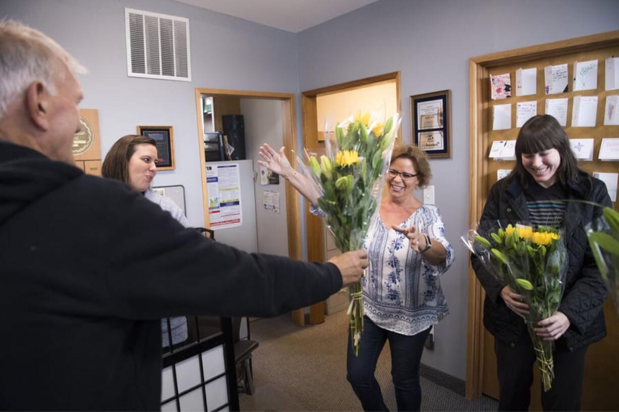 Benno Dobbe, owner of Woodland’s Holland America Flower Gardens, from left, hands flowers to Kim Hulett, Lois Hulett and Shari Hartshorn of Woodland Insurance Agency during Wednesday’s Petal It Forward. Holland America was one of more than 450 participants in the nationwide event, where florists go out and give away free flowers.