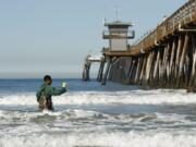 Mar Vista High School sophomore Anthony Gass collects a water sample at the Imperial Beach Pier on Thursday. The school and the Surfrider Foundation have teamed up to monitor water pollution north of Tijuana. K.C.