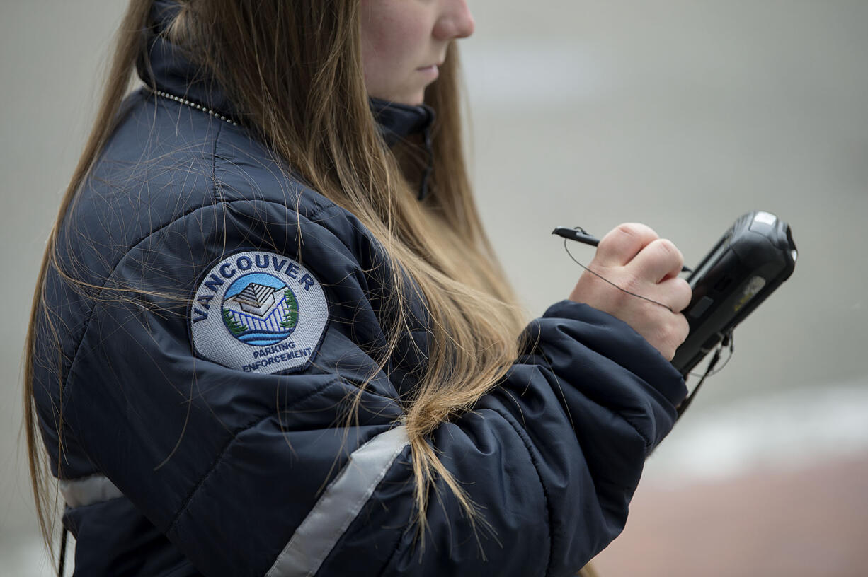 Vancouver Parking Enforcement Officer Jessica Keenan issues a ticket for an expired meter in downtown Vancouver in May 2017. The city of Vancouver's parking services will be reorganized to fall under the Vancouver Police Department starting Monday, according to the department.