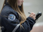 Vancouver Parking Enforcement Officer Jessica Keenan issues a ticket for an expired meter in downtown Vancouver in May 2017. The city of Vancouver's parking services will be reorganized to fall under the Vancouver Police Department starting Monday, according to the department.