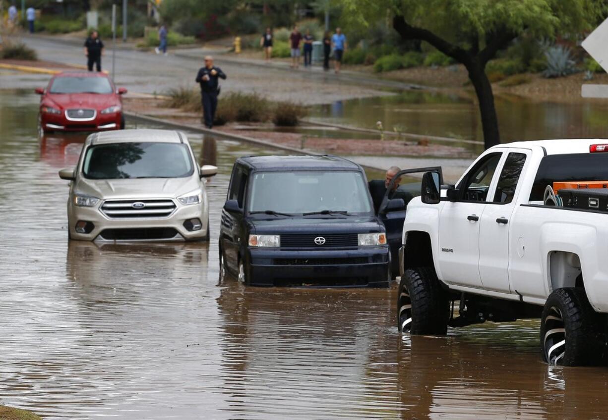 Vehicles wait to get towed from a flooded street during a flash flood as a result of heavy rains from tropical storm Rosa Tuesday, Oct. 2, 2018, in Phoenix. (AP Photo/Ross D.