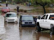 Vehicles wait to get towed from a flooded street during a flash flood as a result of heavy rains from tropical storm Rosa Tuesday, Oct. 2, 2018, in Phoenix. (AP Photo/Ross D.