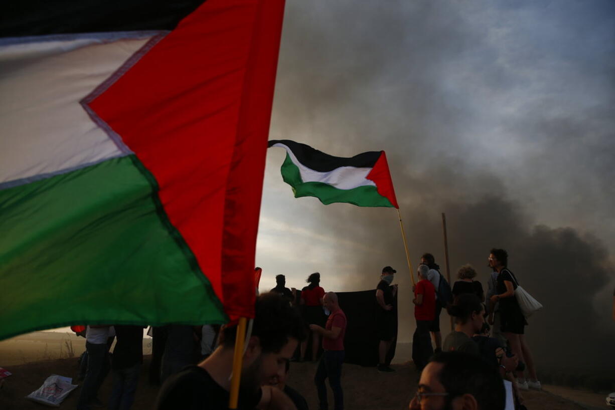 Israeli peace activists hold Palestinian flags during a protest on Israel Gaza border, Friday, Oct. 5, 2018.